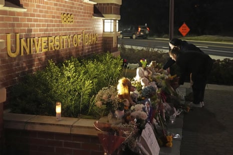 Two people place flowers at a growing memorial in front of a campus entrance sign for the University of Idaho on 16 November 2022 in Moscow, Idaho.