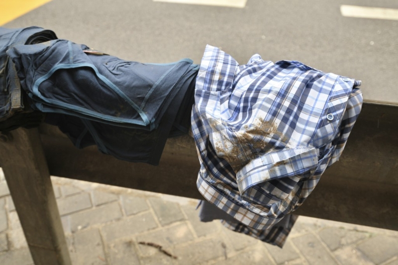 有街档的衣物被黄泥水污染，置于路边防撞栏上晒干。