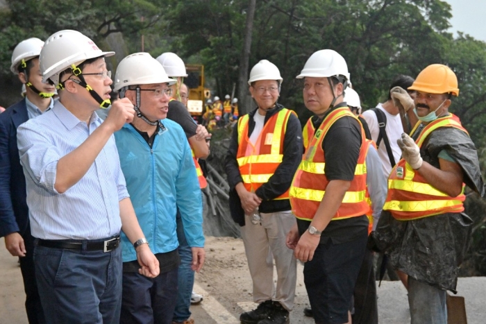 李家超（左一）和运流局局长林世雄（左二）为路面修复工程的工作人员打气。