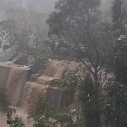 翠林邨彩林楼后山山坡，被大雨不断冲击，沙泥夹杂雨水向下流，形成一道瀑布。 网片截图