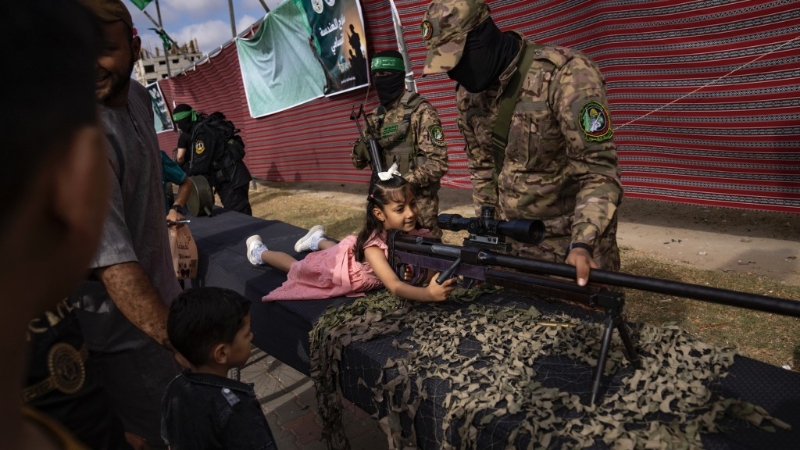巴勒斯坦女孩在加沙走廊中部努赛拉特难民营的哈马斯武器展上摆姿势。 美联社