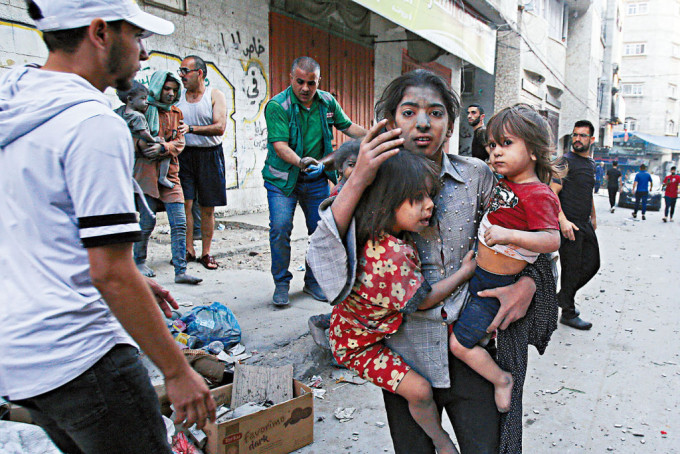以军空袭加沙城，巴勒斯坦妇女抱着两童逃命。