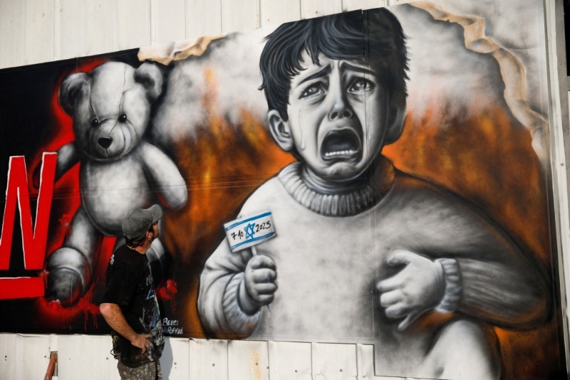 以色列街头画家绘画小孩子哭喊海报，要求哈马斯尽快释放人质。 路透社