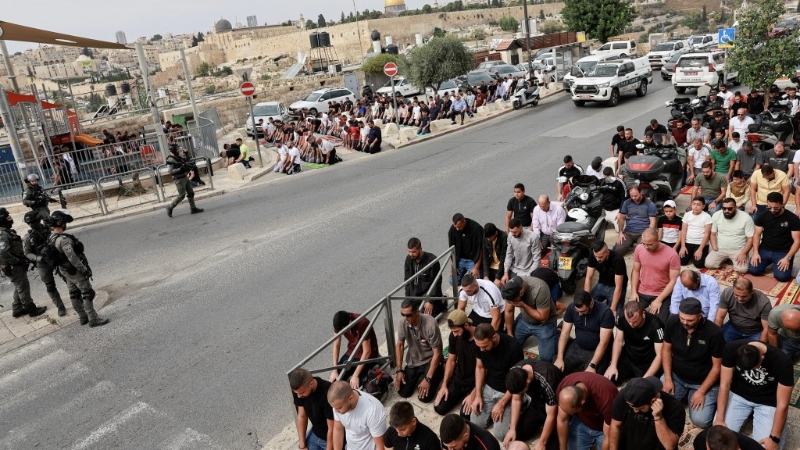 巴勒斯坦穆斯林在耶路撒冷旧城外的一条道路上举行周五祈祷，以色列边境警察站岗。 路透社
