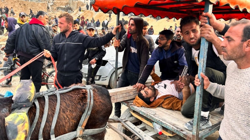 巴勒斯坦人用驴车带着受伤的同伴去等候派发面粉
