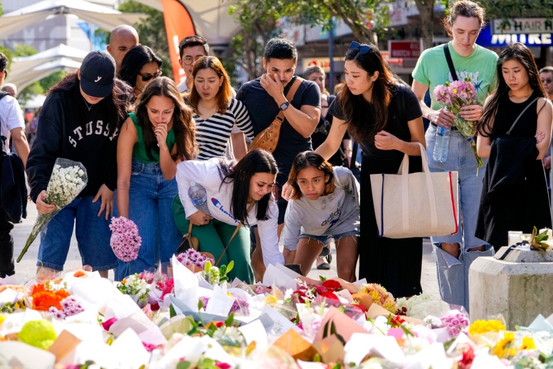 悉尼民众15日在商场附近献花、悼唁死者。