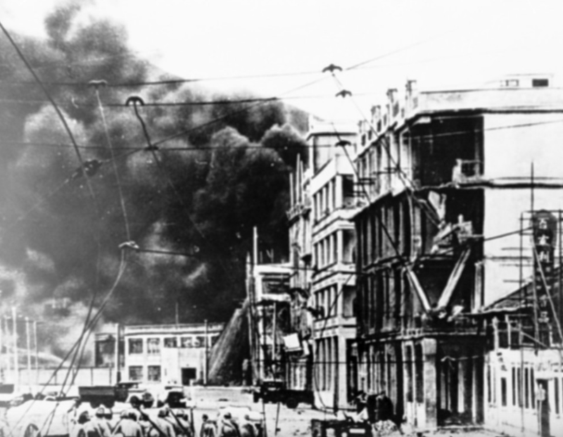 二次大战时日军沿英皇道进发，背景可见北角油库燃烧时产生的浓烟，摄于1940年代