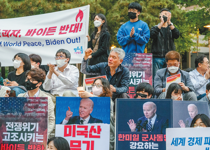 图说：20日在首尔，活动人士手持蜡烛和标语牌，抗议美国总统乔·拜登访问韩国。