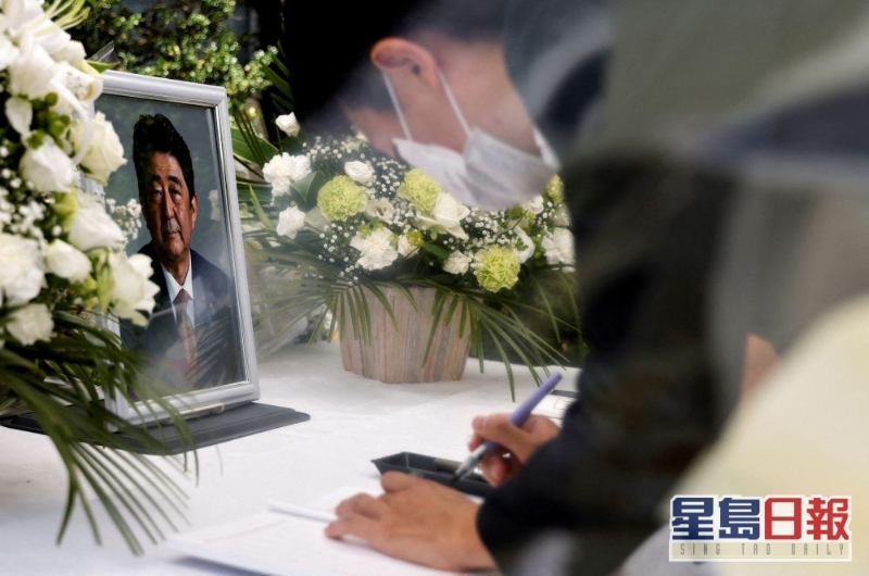 日本東京自民黨總部的祭壇上，一位哀悼者在已故日本前首相安倍晉三的照片前簽名。路透社圖片