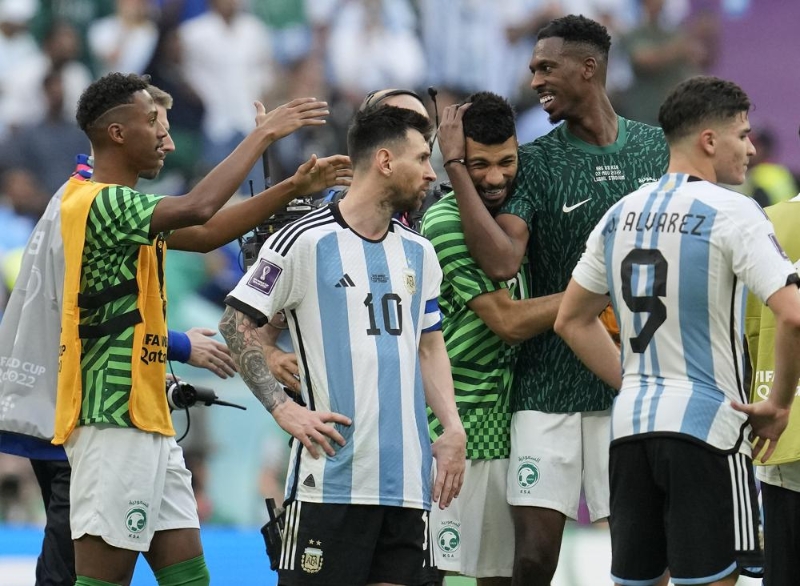 Argentina's Lionel Messi standing beside Saudi Arabia's players celebrating after winning the World Cup group C soccer match between Argentina and Saudi Arabia at the Lusail Stadium in Lusail, Qatar, Tuesday, Nov. 22, 2022. (AP Photo/Natacha Pisarenko)
