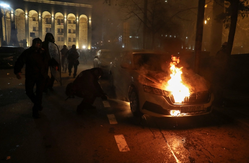 格鲁吉亚大规模示威反对外国代理人法案，执法人员试图靠近一辆被纵火的车灭火。 路透社