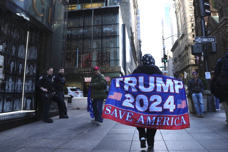 一名婦女在第五大道上行走，舉著一面支持前總統特朗普的旗幟。AP