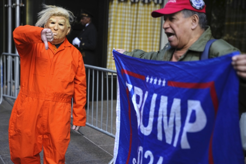 在紐約特朗普大廈外，一名男子（左）身穿囚服諷刺前總統特朗普，向特朗普支持者示威。AP