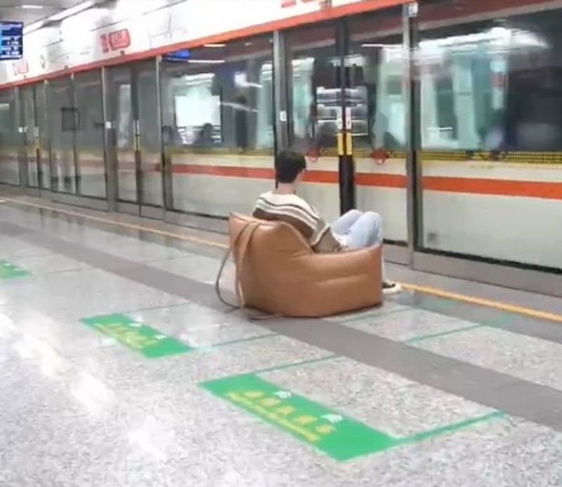 男子坐在自攜梳化在月台上等列車。影片截圖
