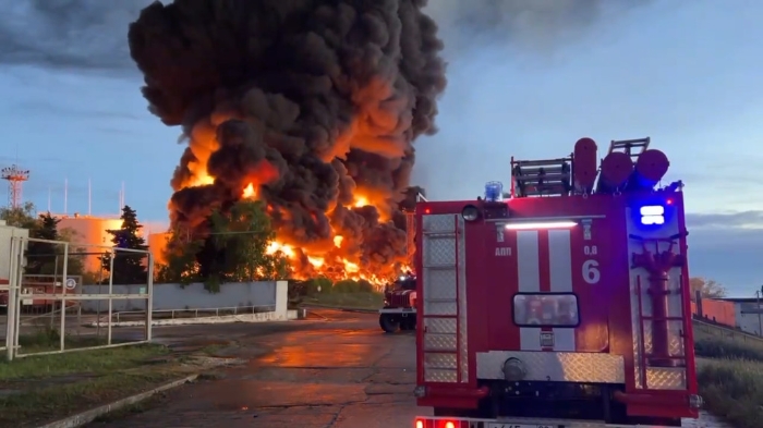 浓烟和火焰从克里米亚储油厂燃烧的油箱中升起，一辆消防车正驶往现场
