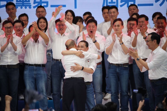 侯友宜（中前）与前高雄市长韩国瑜（中前背对者）在台上拥抱。