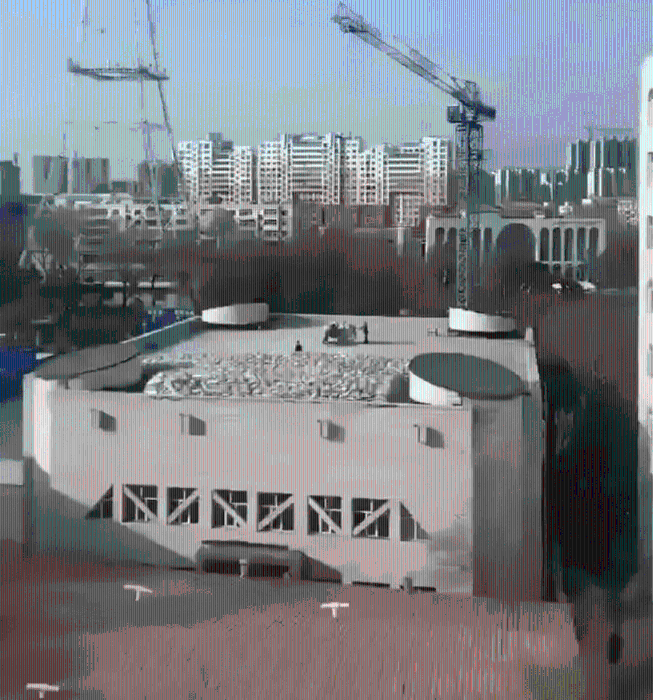 工人在体育馆楼顶堆放袋装材料。 工人在体育馆楼顶堆放袋装材料。