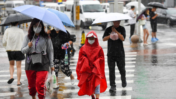 在北京市朝阳区行人冒雨行走在路上
