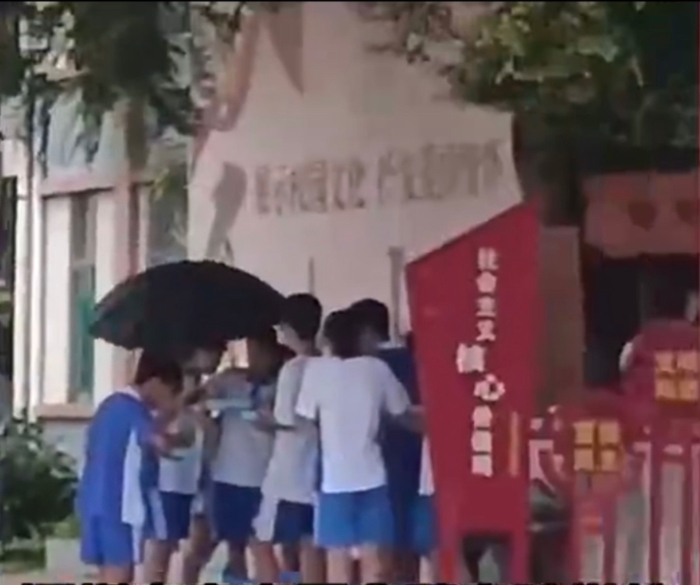 7、8个孩子撑着伞、站着吃饭。