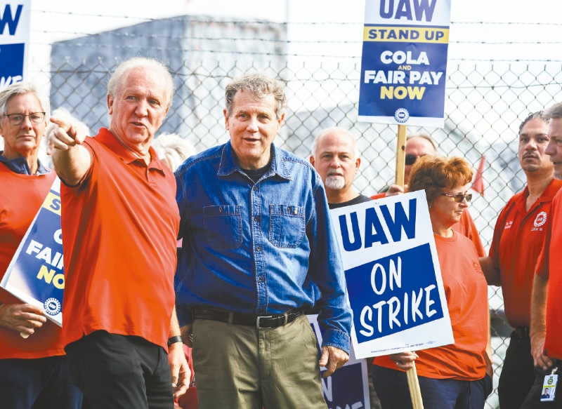 汽车工人联合会进行一系列的零星罢工,针对性打击底特律三大汽车厂,扰乱其生产计划。图为UAW的俄州分会主席鲍姆豪威尔 ( 左 ) 带领罢工纠察。美联社 汽车工人联合会进行一系列的零星罢工,针对性打击底特律三大汽车厂,扰乱其生产计划。图为UAW的俄州分会主席鲍姆豪威尔 ( 左 ) 带领罢工纠察。美联社