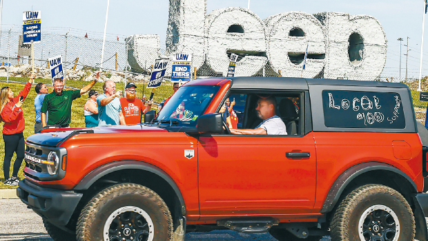 图为工人在厂外罢工。 图为工人在厂外罢工。