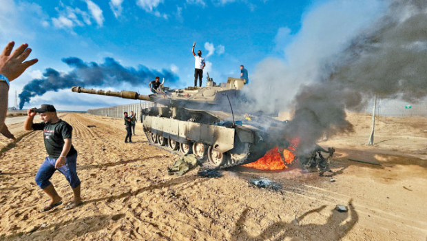加沙地带的巴人在一辆损毁的以军坦克旁庆祝。
