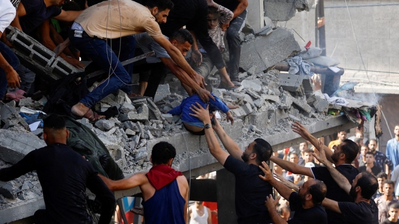 汗尤尼斯住宅建筑被炸出大洞，民众在瓦砾中抱出一个孩子。