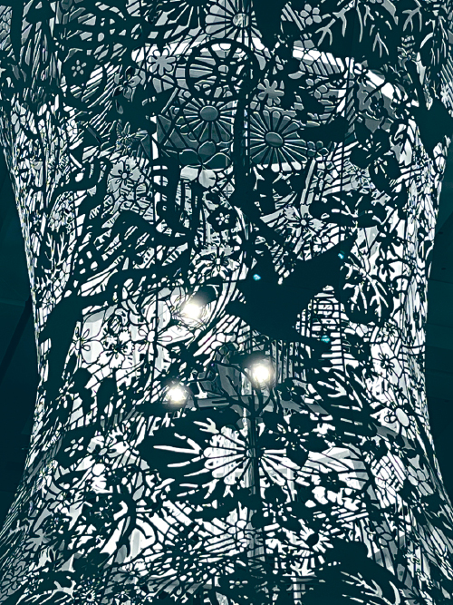 金属雕塑表面的各种植物及动物图案，以镂空雕刻技术创作，强烈的光线投射在动植物图形上，呈现出缓缓移动的阴影。