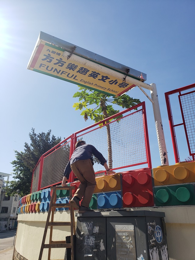 小学部负责人朱先生知悉后，亲自爬高尝试将招牌放下来，但招牌太重不成功。 陈兆龙摄