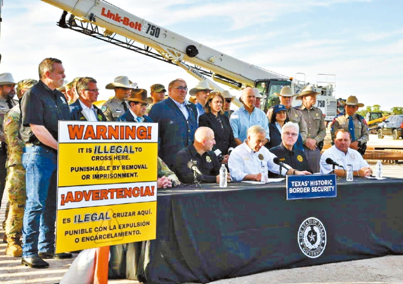 德州州长阿博特（中）18日签署法例，容许德州执法人员拘捕在缺乏法律许可下从墨西哥入境德州的难民，法例将在明年3月生效。 美联社