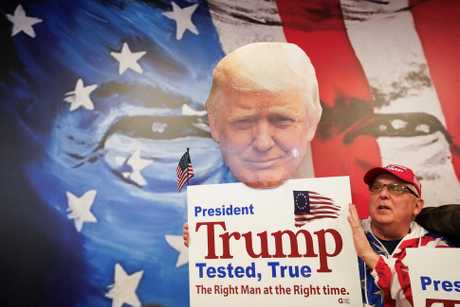 新罕布什尔州一名特朗普支持者举着特朗普肖像和标语牌子。