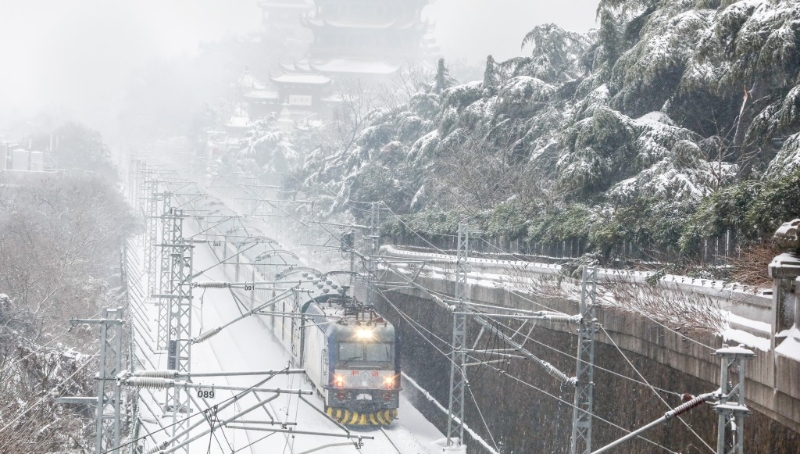 湖北武汉降雪天气持续，内燃机车列车雪中从武汉黄鹤楼旁驶过。