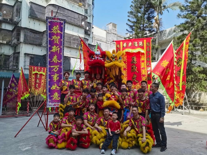 揭阳榕城小女孩林熙悦在路边练习舞狮，恰遇一支专业舞狮表演队路过，为她敲锣擂鼓、呐喊助威。