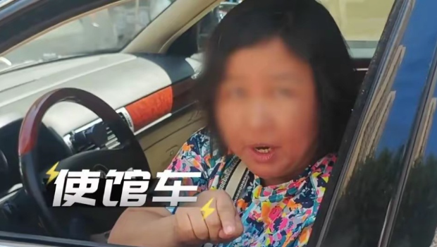 女方将挂有使馆车牌的轿车停在道路中间。 女方将挂有使馆车牌的轿车停在道路中间。