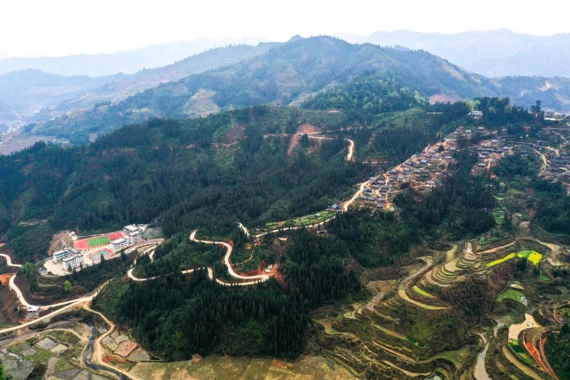 图为群山环抱的贵州省大歹苗寨（右）及大歹小学（左）