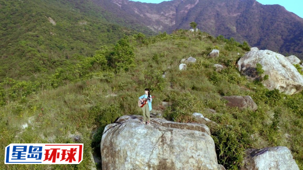 站立山顶、于环山包围的美景下自弹自唱。 站立山顶、于环山包围的美景下自弹自唱。