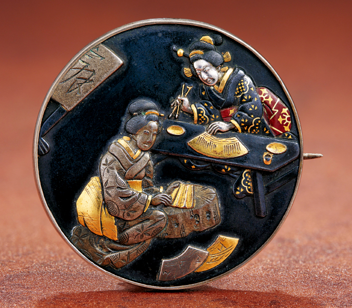 鎏金银赤铜,或以莳绘上色的胸针,描画了造扇的和服女子,是日本1800年代晚期作品,属私人收藏。 鎏金银赤铜,或以莳绘上色的胸针,描画了造扇的和服女子,是日本1800年代晚期作品,属私人收藏。