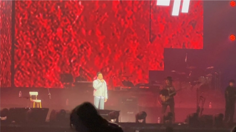 齐秦身穿白色衬衫及银色羽绒服，下身则穿着黑白条纹长裤配运动波鞋，整体造型十分随性休闲。