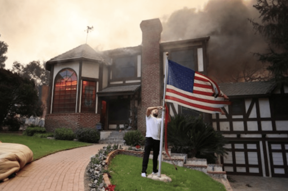 美国加州阿尔塔迪纳,在伊顿大火中,一名男子在燃烧的堂兄家外降下一面旗帜。路透社 美国加州阿尔塔迪纳,在伊顿大火中,一名男子在燃烧的堂兄家外降下一面旗帜。路透社