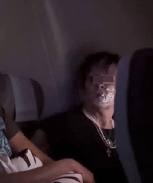 另一张出现在当地媒体的照片，妇人被绑在座位上，嘴巴封上透明胶纸，双目怒瞪着坐在邻座看守她的空姐。.png