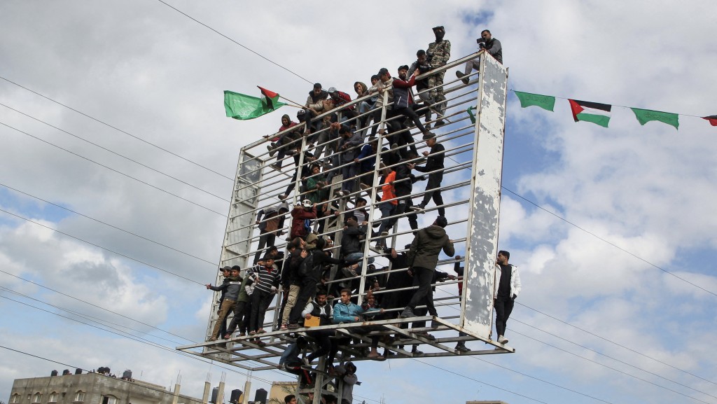 巴勒斯坦人爬上告示牌结构架观看释放人质的仪式。 巴勒斯坦人爬上告示牌结构架观看释放人质的仪式。