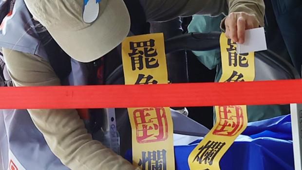 图为罢免团体工作人员在载运资料的推车上贴著罢免烂委的封条