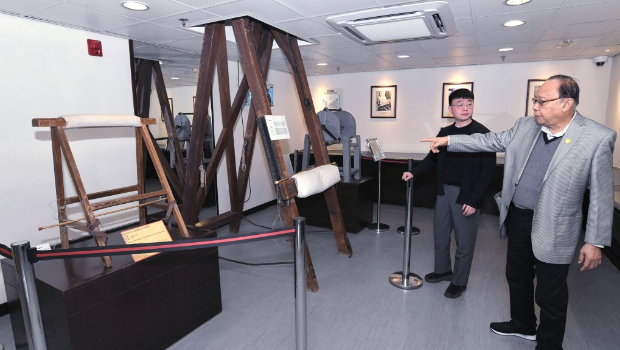 香港惩教博物馆助理馆长马祺俊（左）及博物馆助理李钰麟（右）介绍馆内的大型笞刑架。