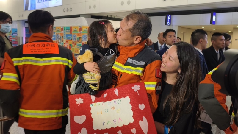 有搜救队员在机场与妻子及4岁女儿相拥。