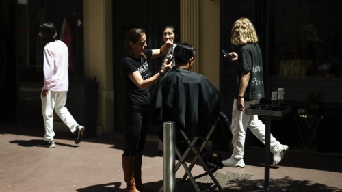 法国南部大停电，理发店光线不足，发型师和顾客移到大街上利用阳光剪发。 路透社