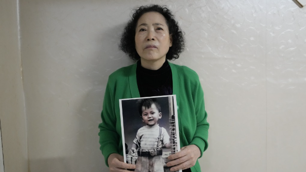 崔英子拿着失踪儿子的照片。
