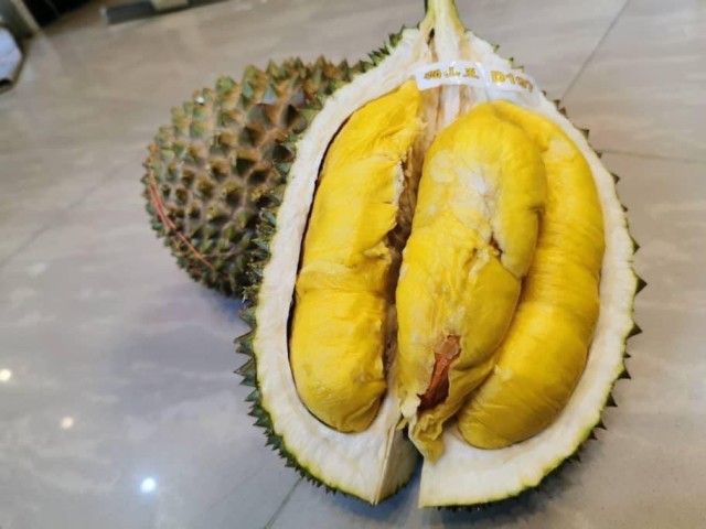 一名妇女在超市走路，涉嫌用裸手打开榴莲。肉