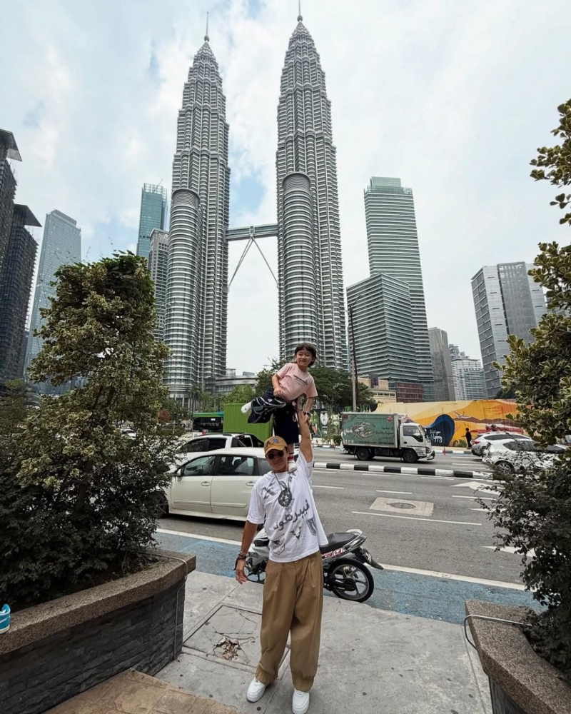 陈山聪举起囝囝影相，以地标双子塔做背景。