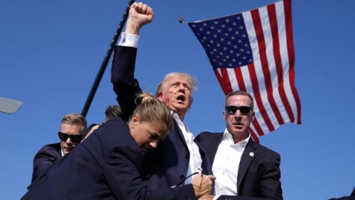 特朗普去年在宾州造势遇刺，右耳受伤流血，但他展现不屈，举拳高喊战斗。