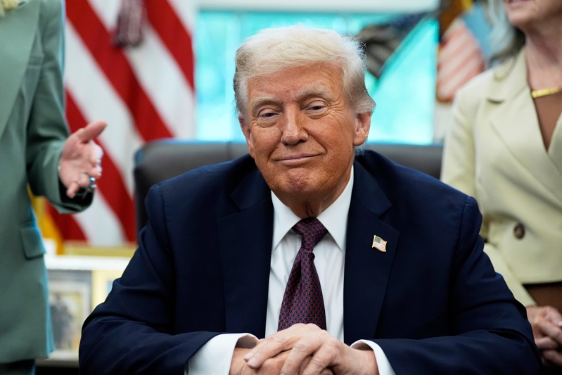 美国总统特朗普于2025年9月15日在华盛顿白宫椭圆形办公室内，签署一份备忘录前倾听。